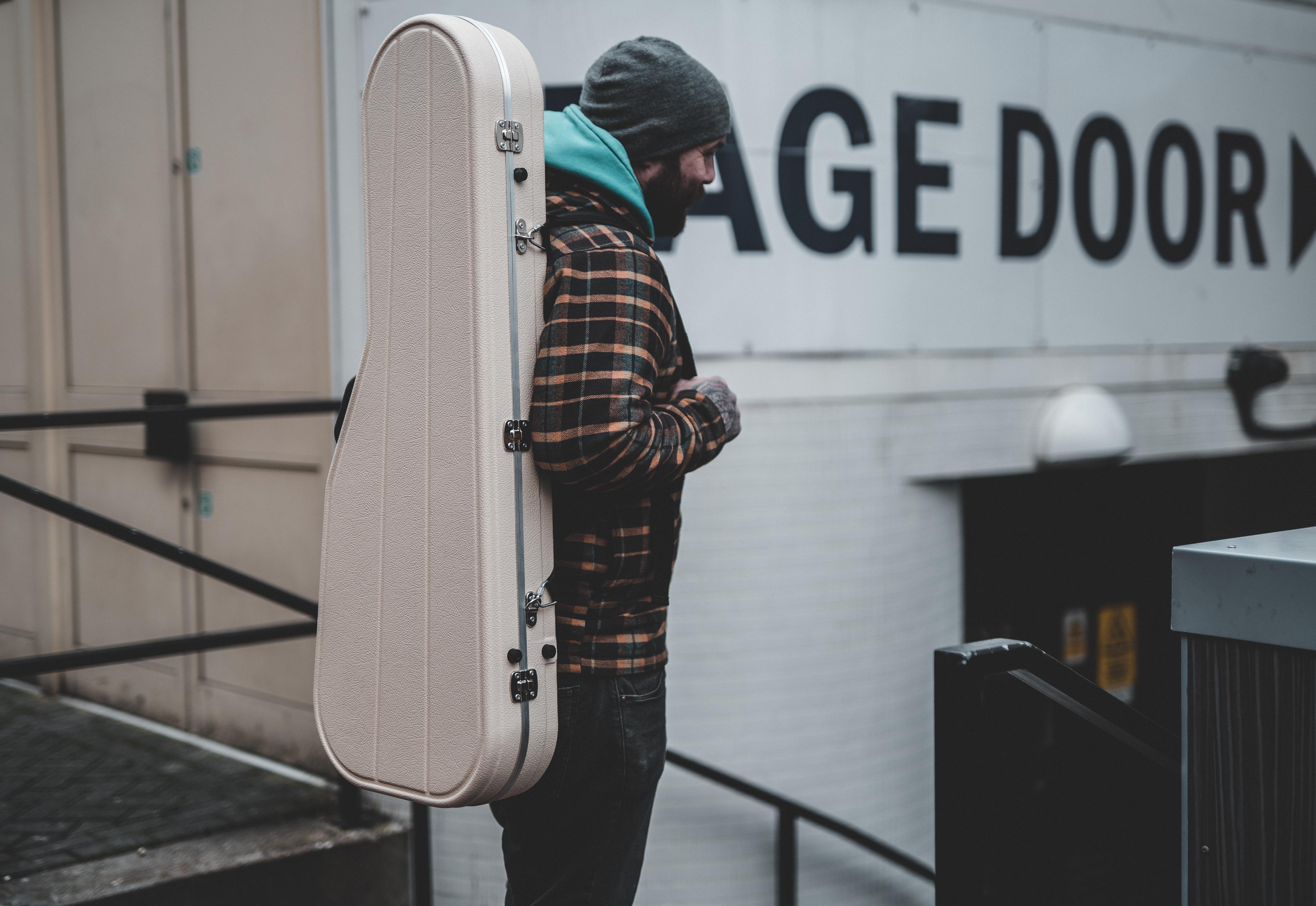 Musician wearing a Hiscox case as a backpack outside a stage door